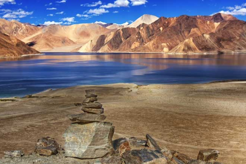 Scenic view of Leh-Ladakh with snow-capped mountains, winding roads, and a Buddhist monastery – perfect destination for adventure and nature lovers.